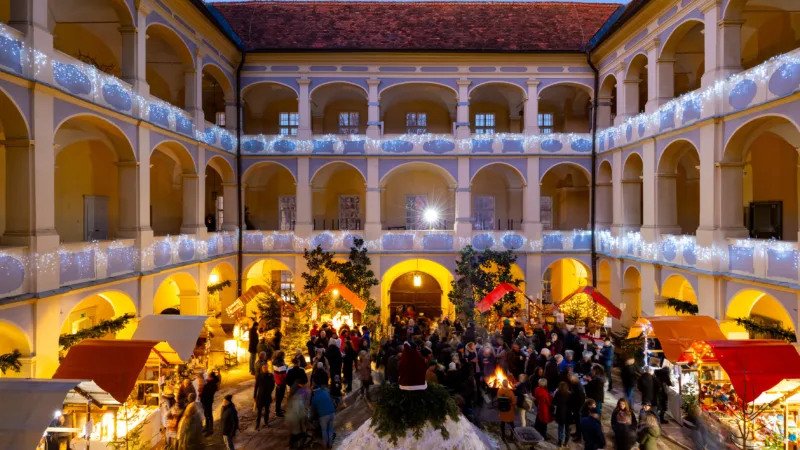 Baroque castle courtyard, illuminated for Christmas, market stalls, people