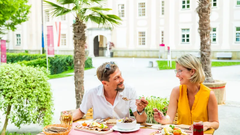 Man and woman at a laid table on a terrace, castle in the background