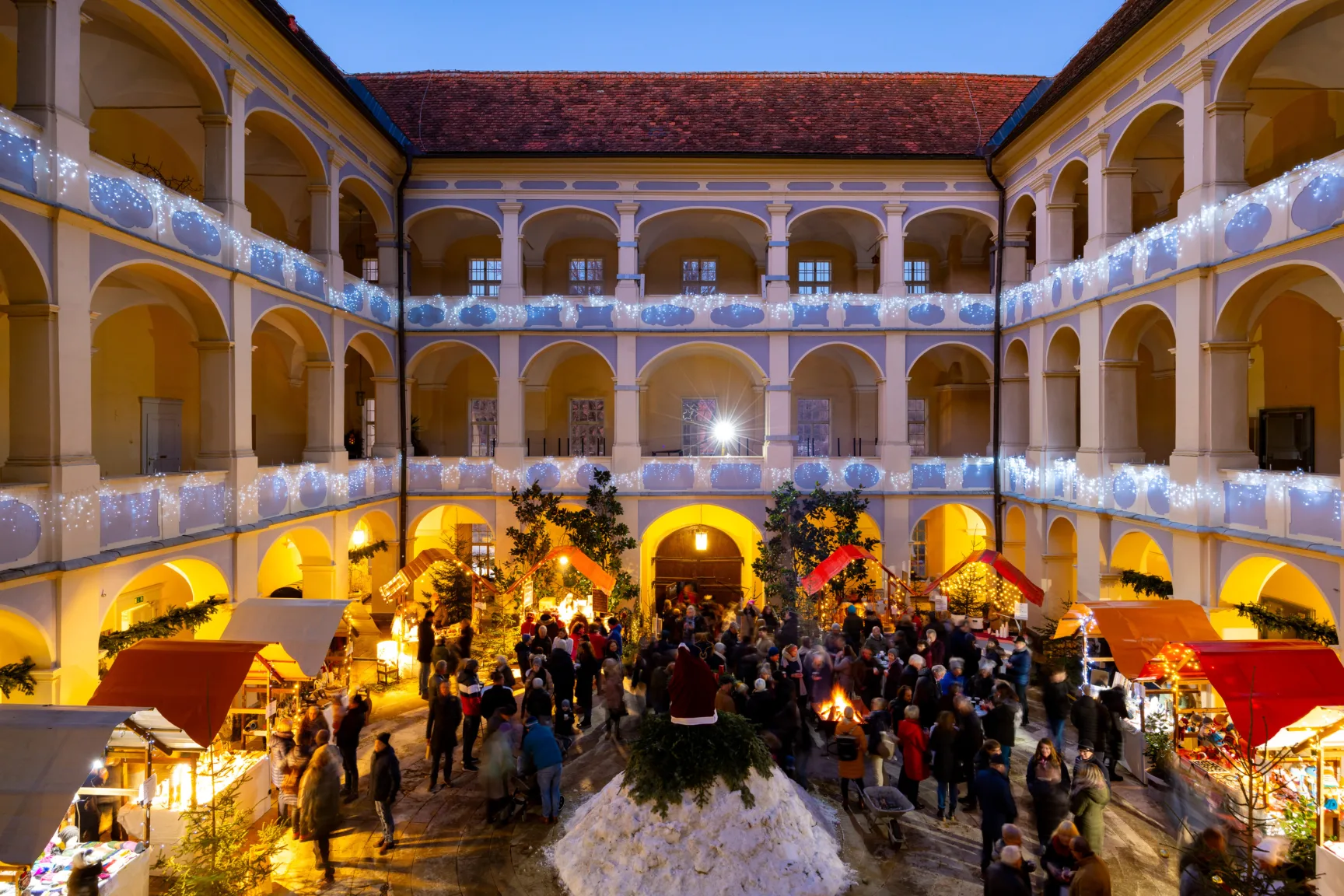 Baroque castle courtyard, illuminated for Christmas, market stalls, people